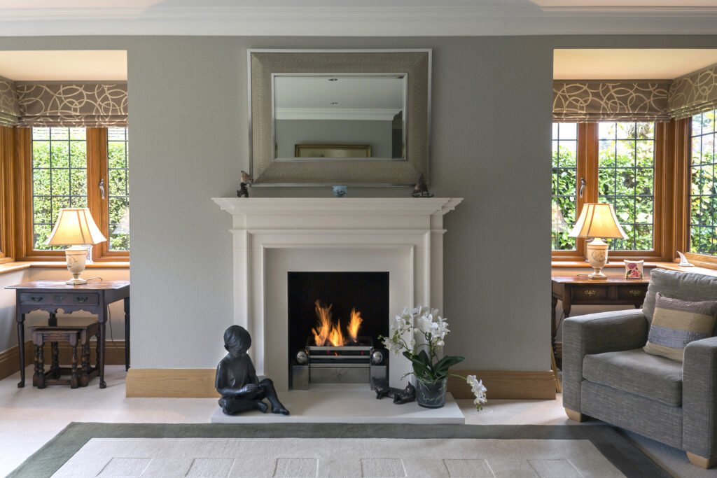 Elegant living room with white fireplace, mirror, and burning fire